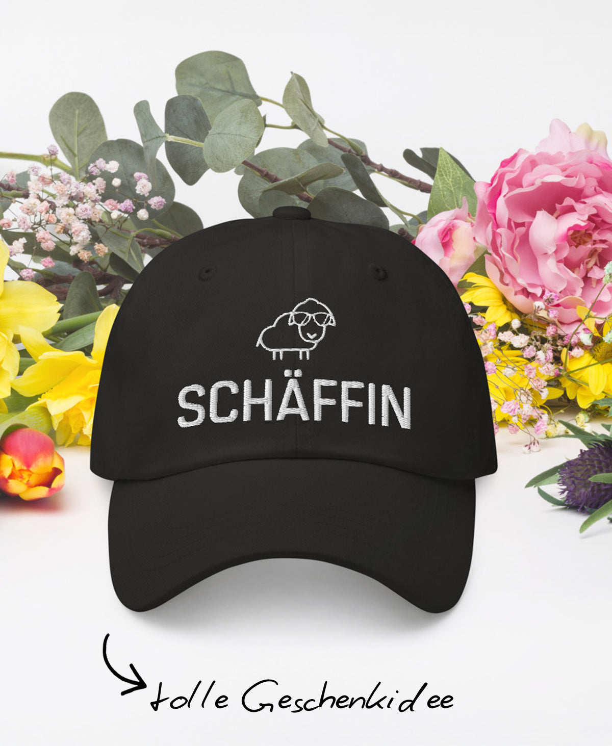 Schwarze Schäffin Kappe mit SCHÄFFIN Stick und kleinem Schaf-Icon; umgeben von Blumen und Text: ‚tolle Geschenkidee’.