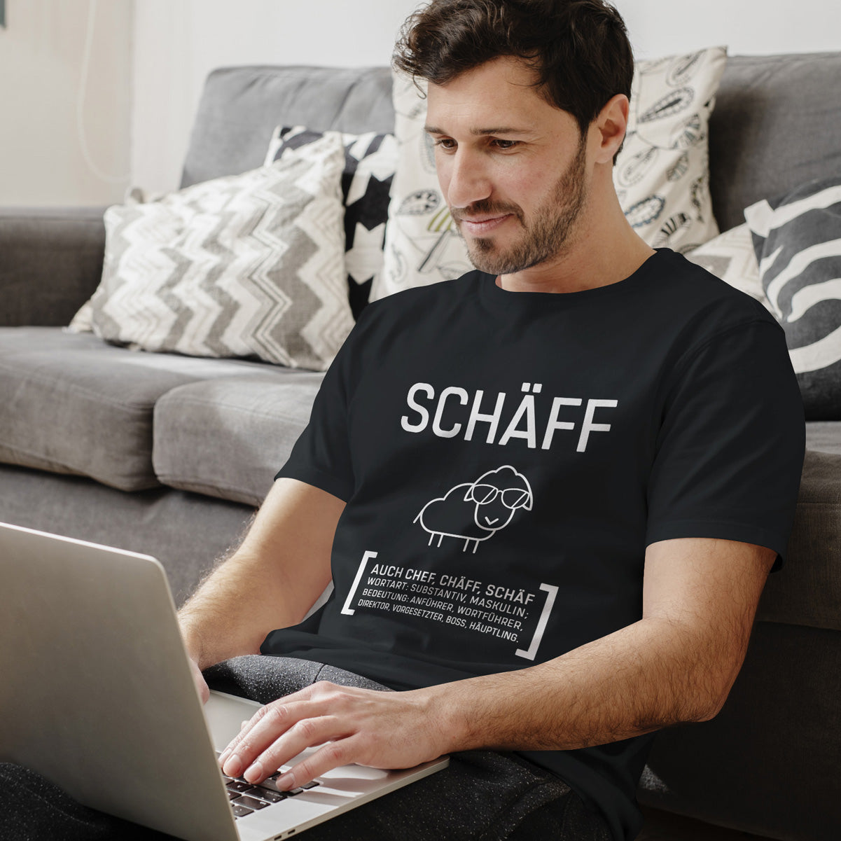 Mann auf dem Sofa im schwarzen SCHÄFF T-Shirt – Lässiges Geschenk für den Chef oder Kollegen, hochwertiger Druck.
