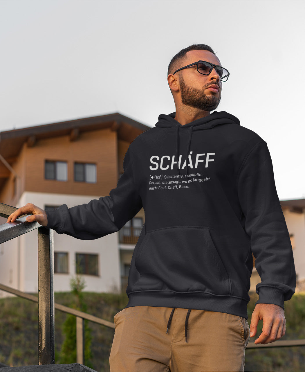 Ernster Mann mit Brille am Treppengeländer trägt SCHÄFF – Chef Definition Bio-Hoodie in Navy