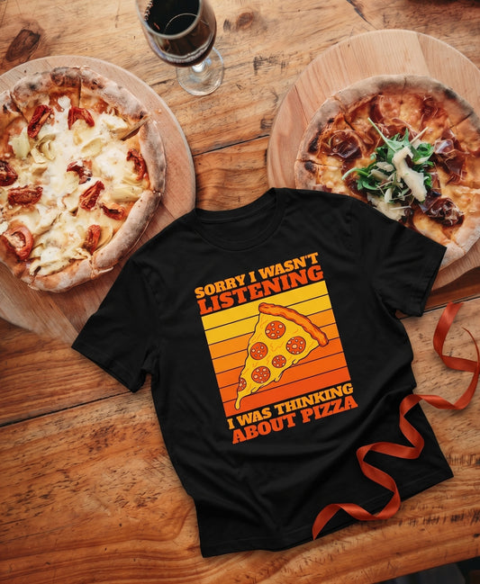 SCHÄFF Sorry I Wasn't Listening Pizza Bio T-Shirt in Farbe Scharz mit zwei Pizzen einer Geschenkschleife und einem Glas Wein.