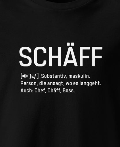 Ausschnitt eines Schwarzen T-Shirt mit weissem Frontaufdruck im Wörterbuch-Stil: SCHÄFF – Substantiv, maskulin. Person, die ansagt, wo es langgeht. Auch: Chef, Chäff, Boss.