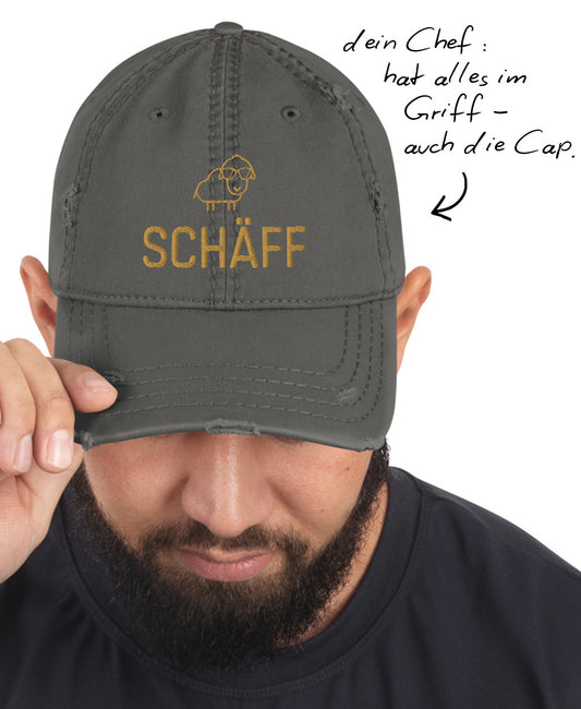 Mann mit grauem Schäff Dad-Hat im Used-Look und Hinweis: ‚dein Chef: hat alles im Griff - auch die Cap.’