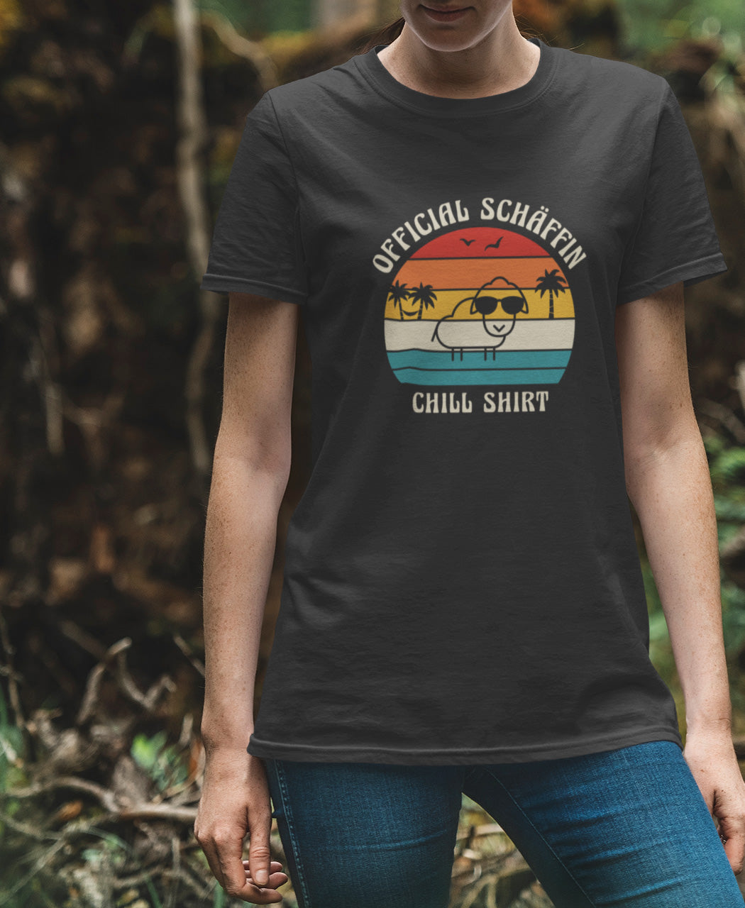 Frau trägt SCHÄFFIN – Official Chill Shirt  Bio T-Shirt in Anthrazit, Schaf mit Sonnenbrille, Palmen und Retro Streifen in Sunset Farben