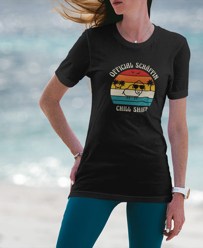 Frau am Strand trägt SCHÄFFIN – Official Chill Shirt  Bio T-Shirt in Schwarz, mit lustigem Schaf mit Sonnenbrille, Palmen und Retro Streifen in Sunset Farben