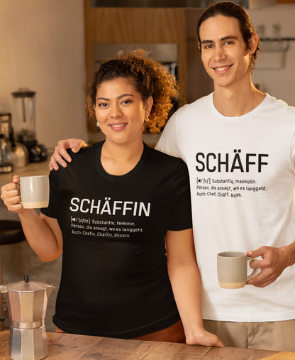 Frau mit Kaffeetasse im Cafe trägt Schwarzes SCHÄFFIN – Chefin Definition Bio T-Shirt mit weisser Aufschrift. Dahinter Mann mit Kaffeetasse trägt weisses SCHÄFF – Chef Definition Bio T-Shirt mit schwarzer Aufschrift.