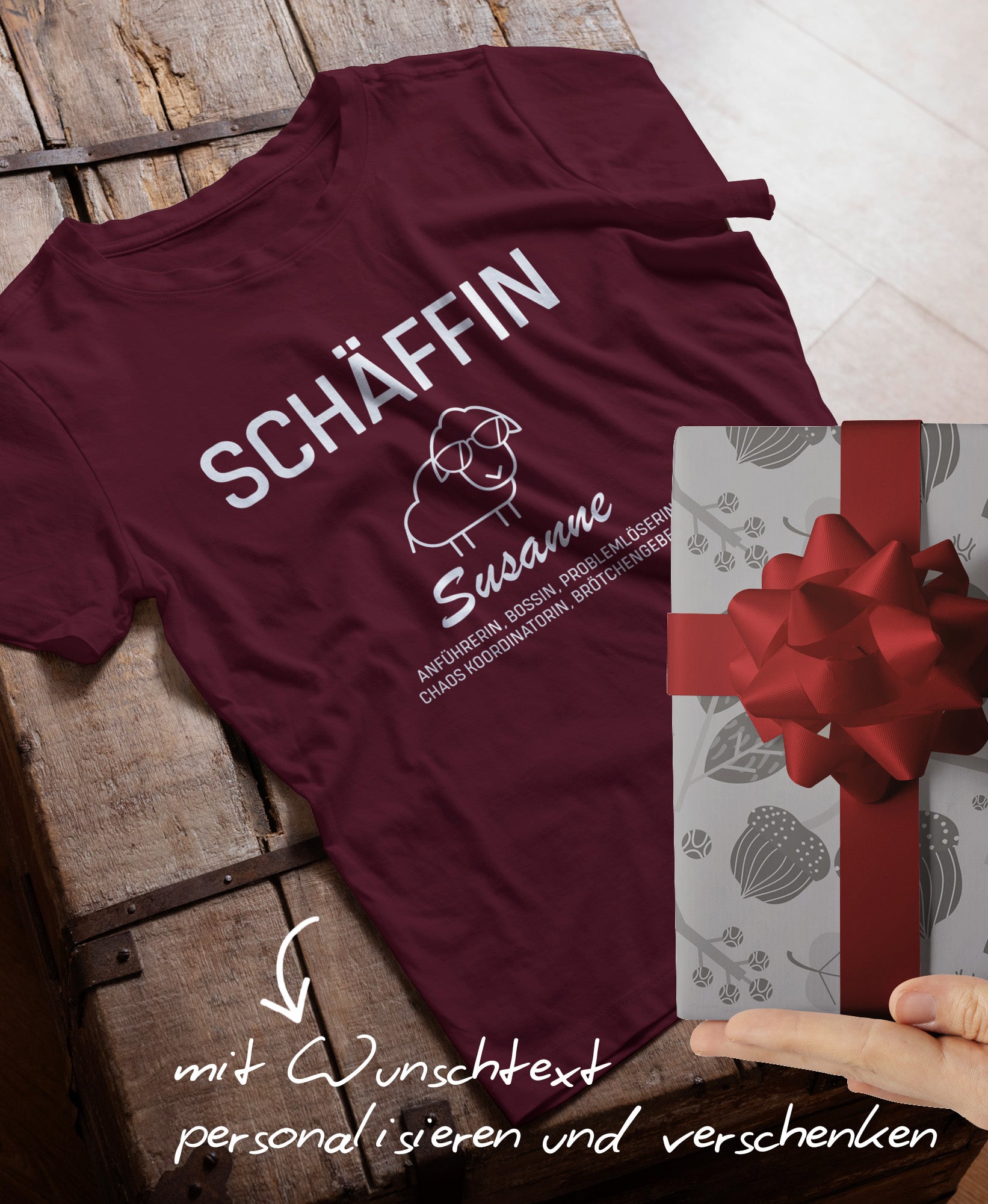 Dunkelrotes T-Shirt mit personalisiertem Schäffin-Aufdruck ‚Susanne‘; davor ein Geschenkpaket mit roter Schleife und dem Hinweis ‚mit Wunschtext personalisieren‘.