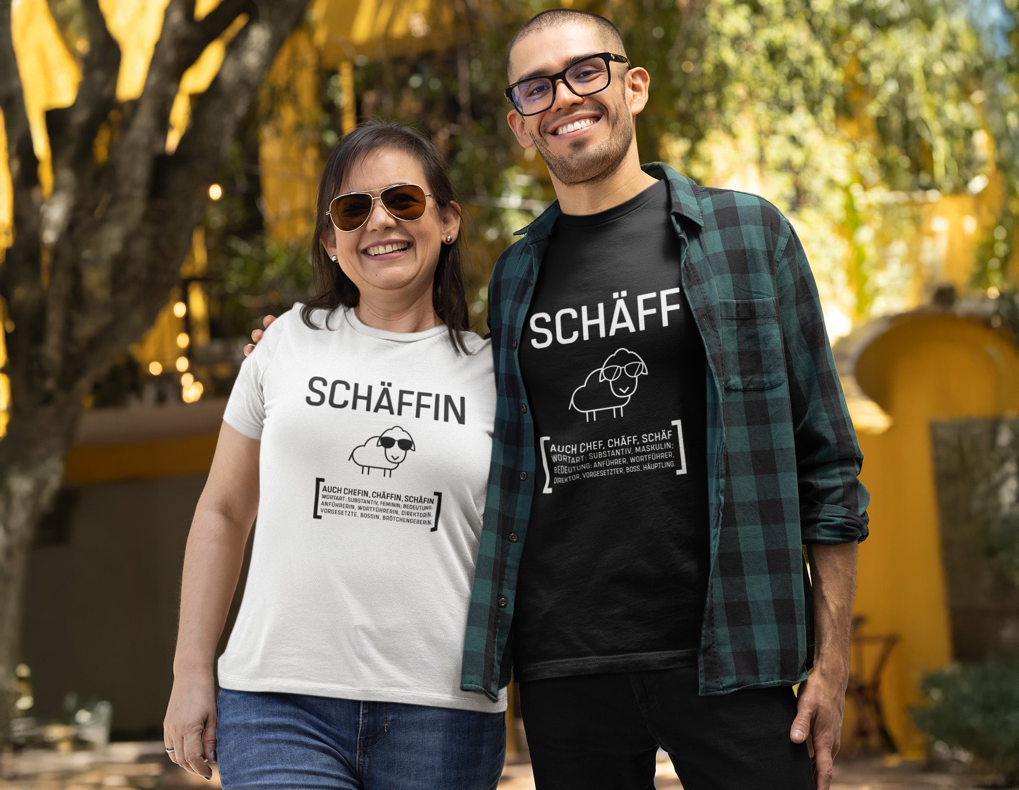 Frau und Mann lächeln im Freien in T-Shirts mit den Aufdrucken „Schäffin“ und „Schäff“ inklusive Schaf-Logo und humorvoller Duden-Definition.