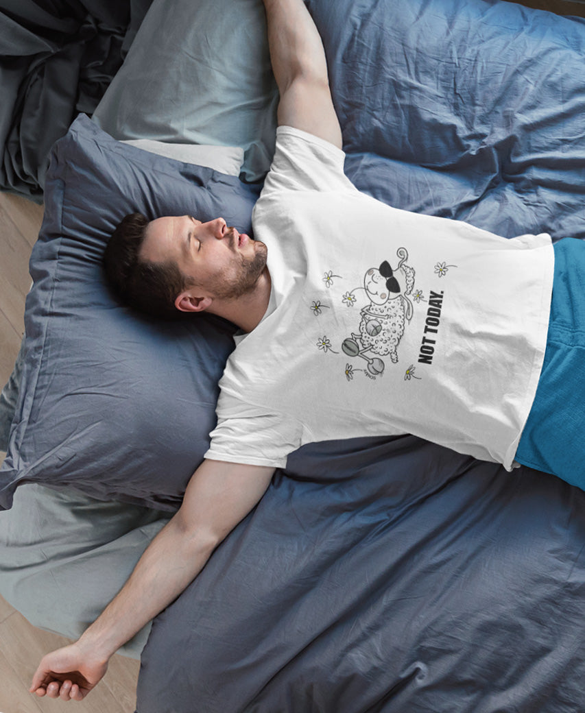 Mann liegt entspannt auf Bett und trägt SCHÄFF Not Today Schaf Bio T-Shirt mit Comic Schaf und Sonnenbrille.