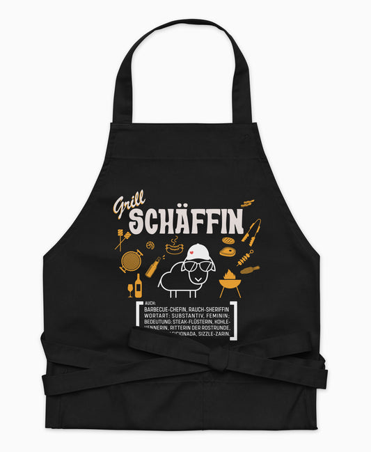 Schwarze Premium Grill SCHÄFFIN Kochschürze aus Bio-Baumwolle mit witzigem Wörterbuch-Design und zwei großen Vordertaschen auf weißem Hintergrund.