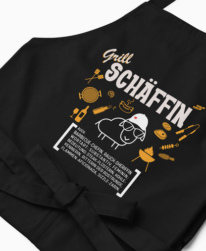 Nahaufnahme der schwarzen Grill SCHÄFFIN Schürze mit detailreichem, orange-weißem Aufdruck.