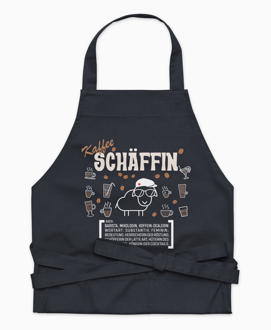Dunkelblaue Premium Kaffee SCHÄFFIN Kochschürze aus Bio-Baumwolle mit witzigem Wörterbuch-Design und zwei großen Vordertaschen auf weißem Hintergrund.
