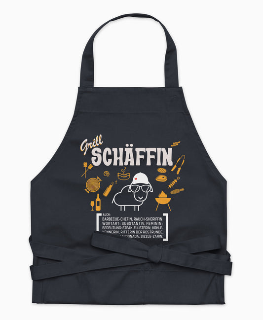 Dunkelblaue Premium Grill SCHÄFFIN Kochschürze aus Bio-Baumwolle mit witzigem Wörterbuch-Design und zwei großen Vordertaschen auf weißem Hintergrund.