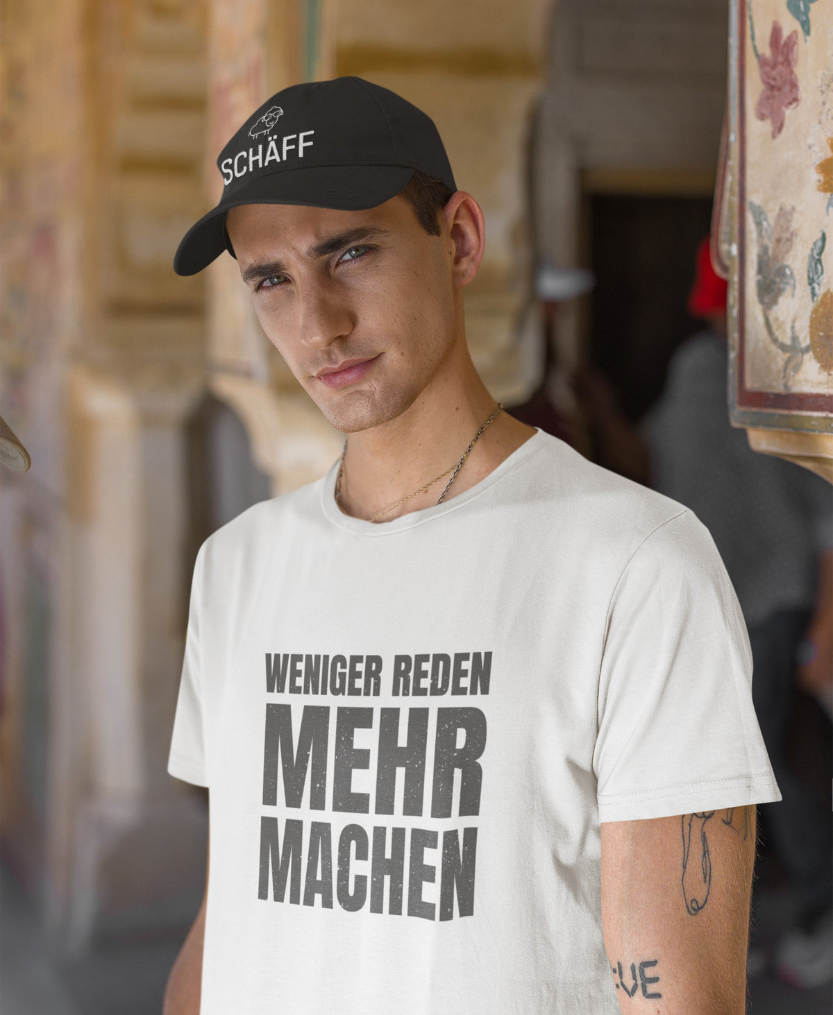 Sympatischer Mann mit dunkelgrauer SCHÄFF – Bestickte Chef Cap Classic und T-Shirt mit Aufdruck: weniger reden mehr machen