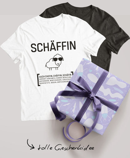 Schwarzes und weisses Schäffin T-Shirt; daneben ein verpacktes Geschenk mit lila Schleife und der Schriftzug ‚tolle Geschenkidee‘.