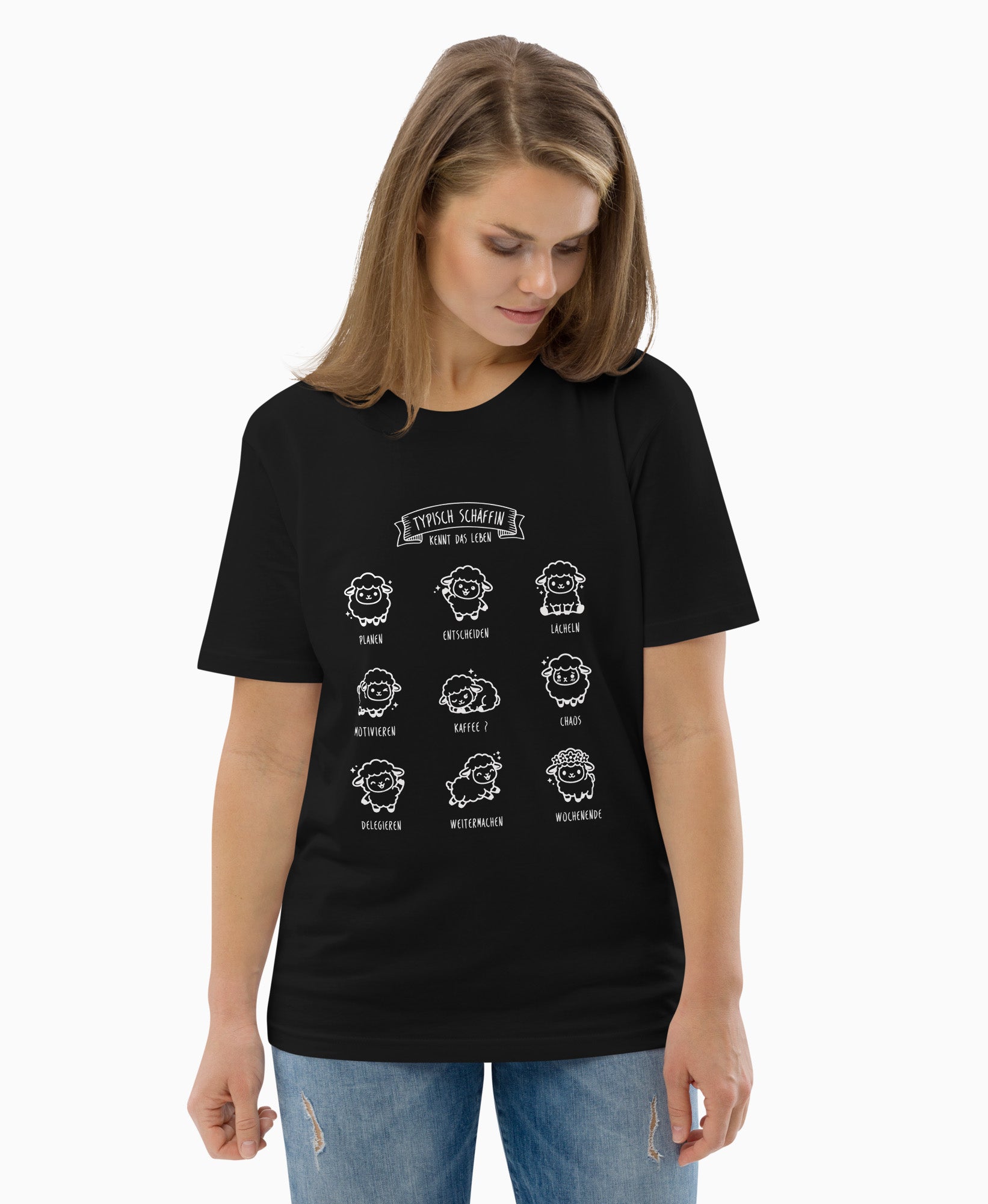 Frau trägt schwarzes Bio-T-Shirt mit weißem SCHÄFFIN Typisch Schäffin / Kennt das Leben Schaf Motiv. Darauf sieht man 9 lustige Kawaii Schäfchen mit kleinem Text und Bezug zum Arbeitsalltag.
